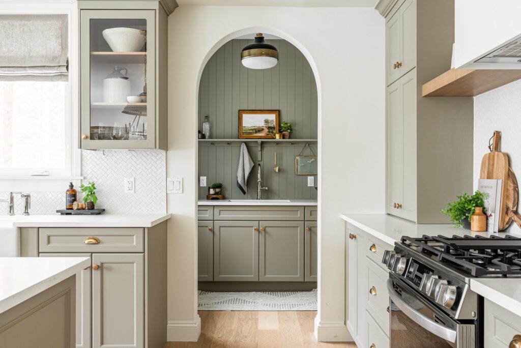 A green pantry design with vertical shiplap and a sink