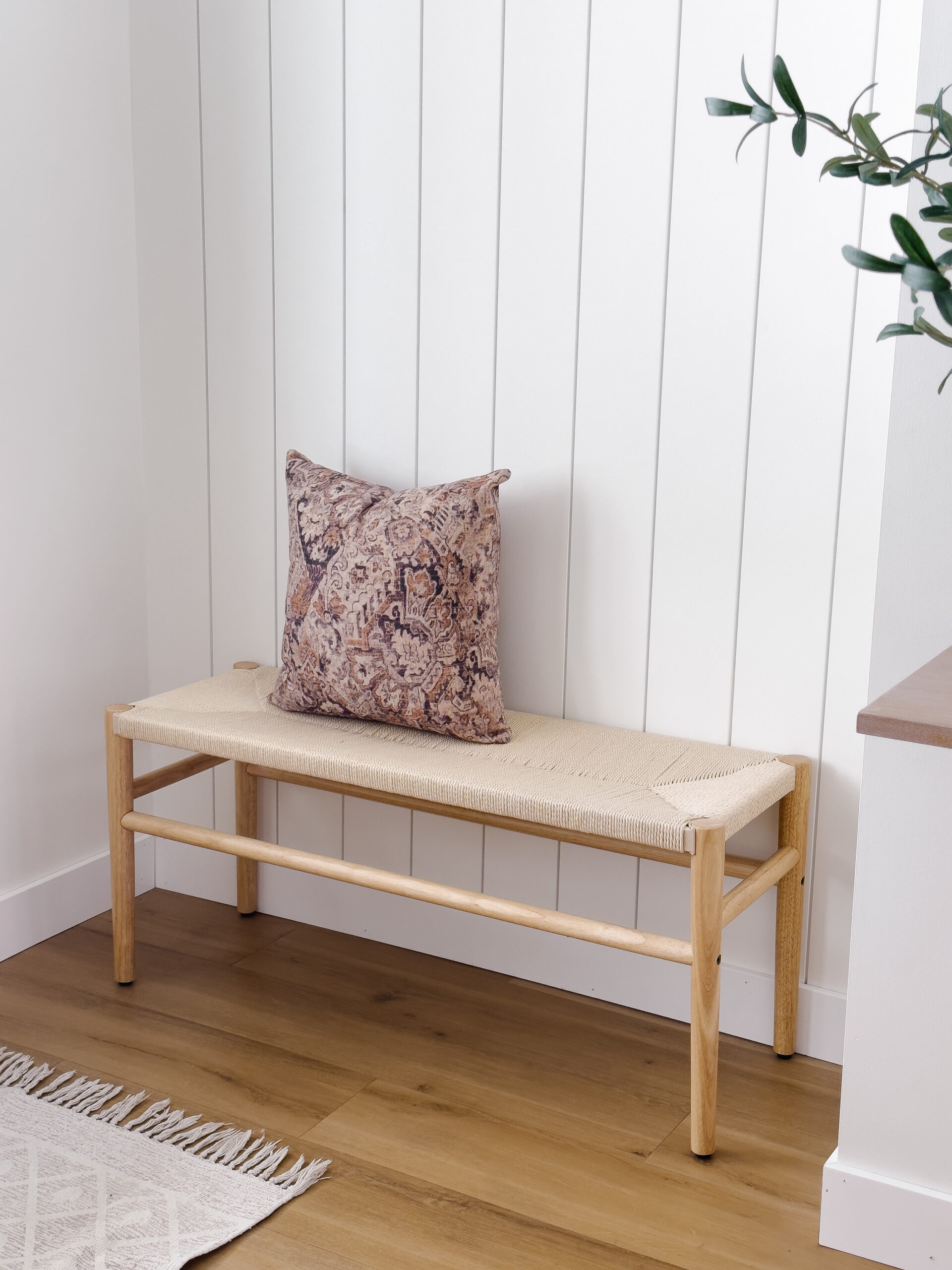 modern wicker bench with pillow in entrance nook