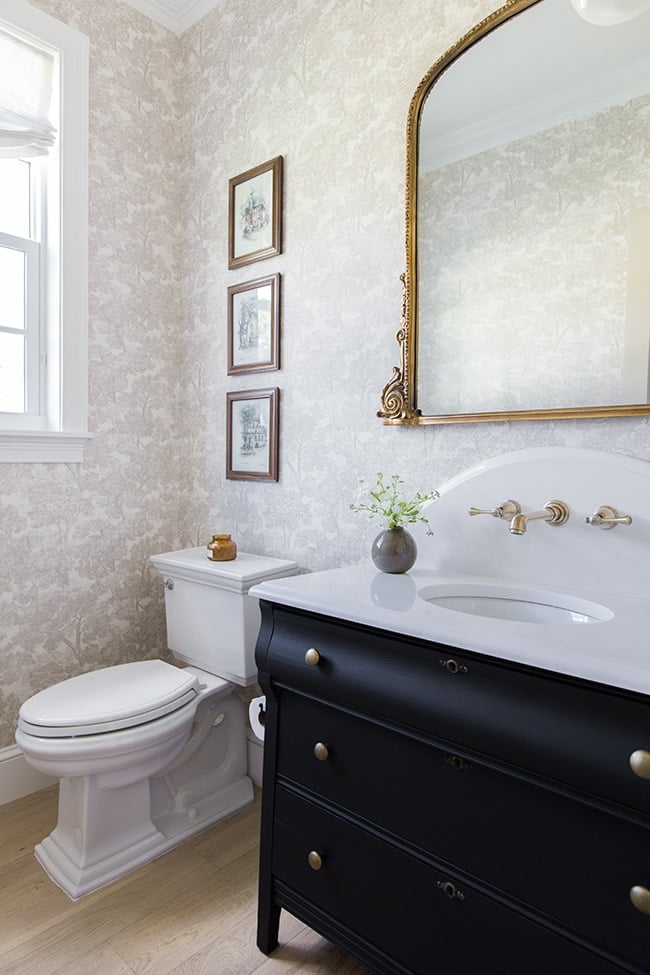 Wallpapered powder bathroom with black vanity