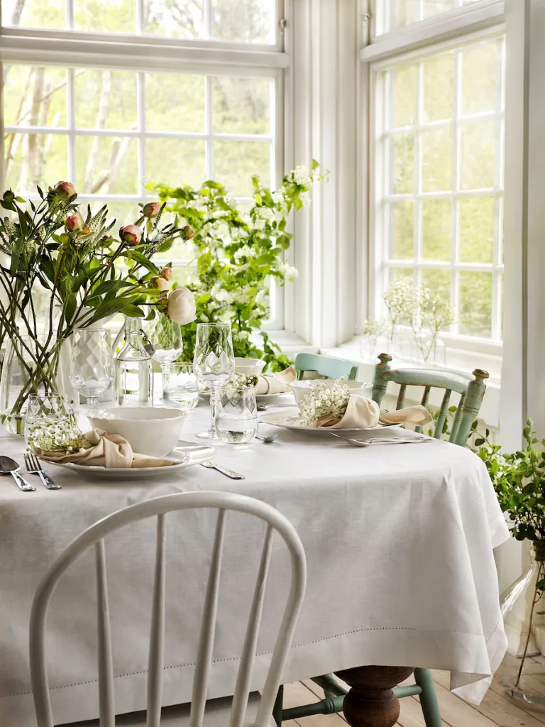 Bright easter table setting idea with lots of greenery and white plates