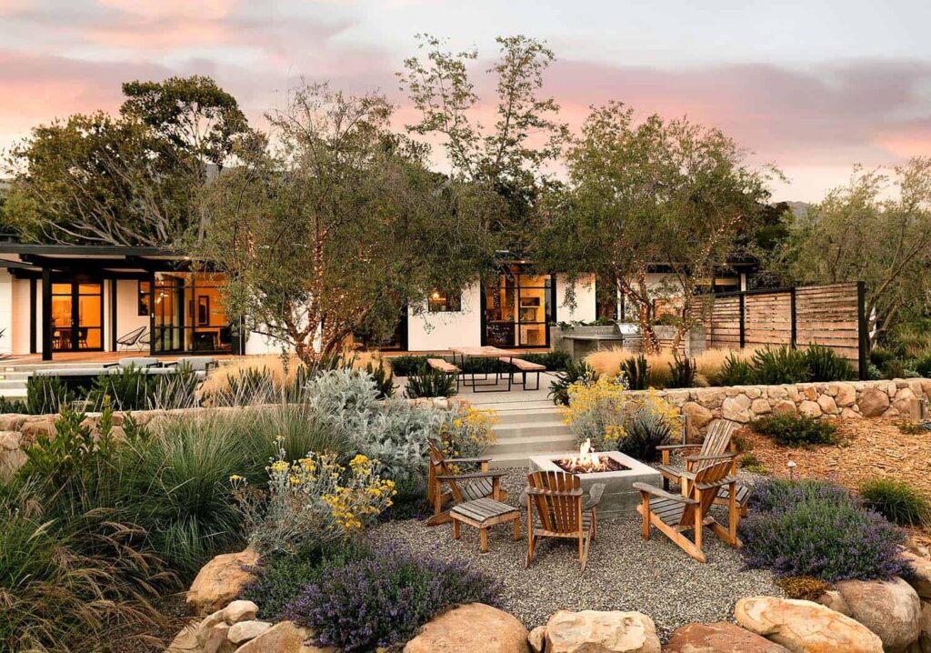 Modern fire pit design surrounded by boulders and flowers